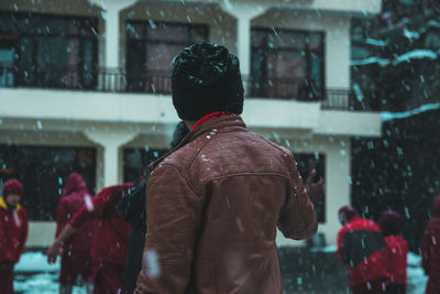 Rear view of man standing on snow covered city