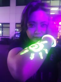 Portrait of woman with illuminated lighting equipment at night