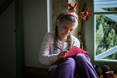 Girl in fun hat writes letter for santa and dreamily waits for gifts on christmas. winter holidays