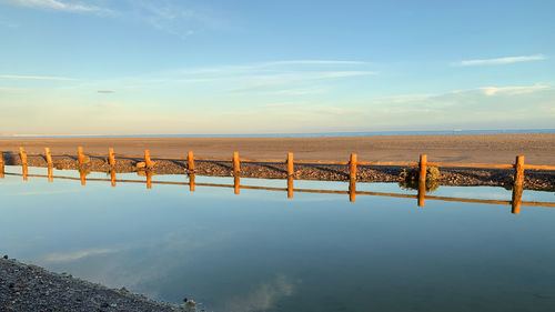 Wooden posts in sea against sky