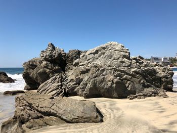 Rock formation on beach against clear blue sky