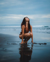 Woman wearing sunglasses at beach against sky