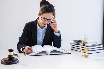 Female lawyer reading book at table in courtroom