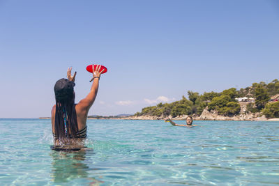 Happy young couple playing with a plastic disc in the sea. travel, vacation and fun