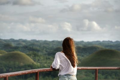 Rear view of woman standing on railing against mountain
