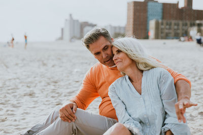 Smiling couple sitting at sandy beach