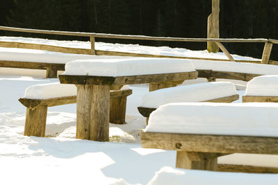 Wooden bench on snow covered field during winter