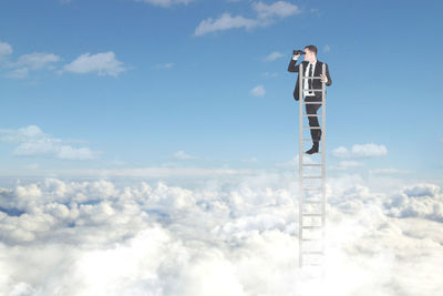 Digital composite image of businessman standing on ladder in cloudscape