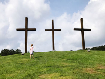Girl standing on a field at the cross against sky