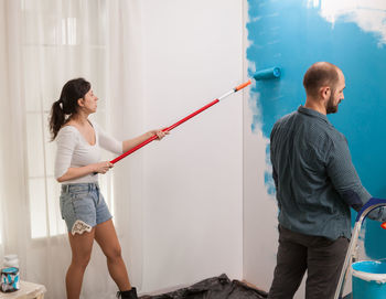 Side view of young couple standing against wall