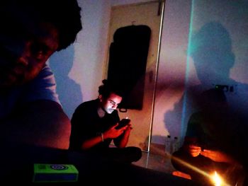 Man photographing through smart phone while sitting in illuminated building