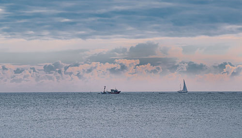 Sailboats sailing on sea against sky during sunset