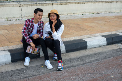 Full length of young couple sitting outdoors