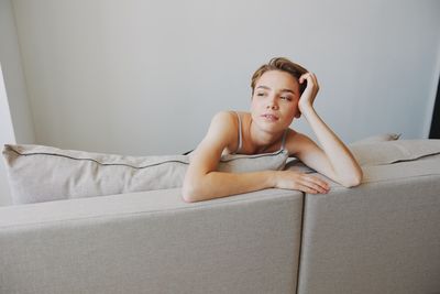 Portrait of young woman sitting on sofa at home