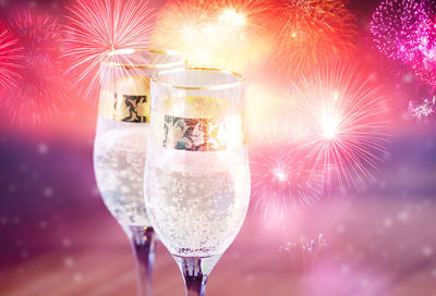 Close-up of wineglass against illuminated christmas lights at night