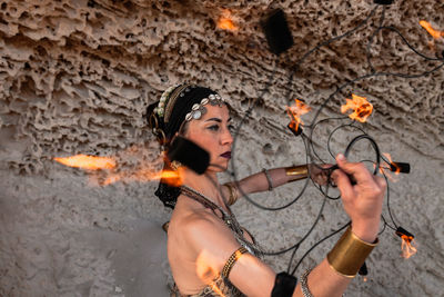 Female performer with fire fans on the beach rehearsing her performance.