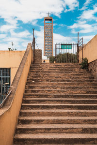 Low angle view of staircase amidst buildings against sky