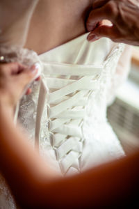 Cropped hands of woman dressing bride during wedding ceremony