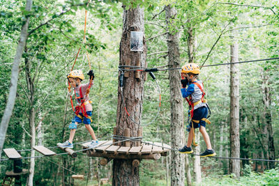 Full length of father and son on tree trunk in forest