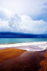 Scenic view of beach against cloudy sky