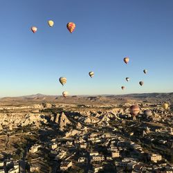 Hot air balloons flying over landscape against clear sky