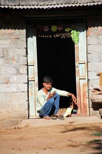 Full length of man sitting outside building