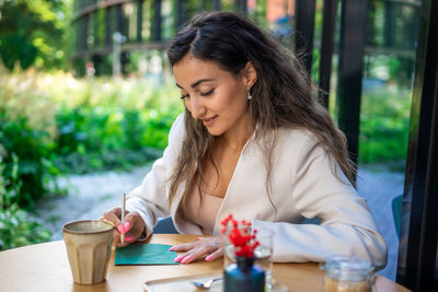 Young woman using mobile phone while sitting at cafe