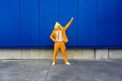 Full length of man standing against blue wall