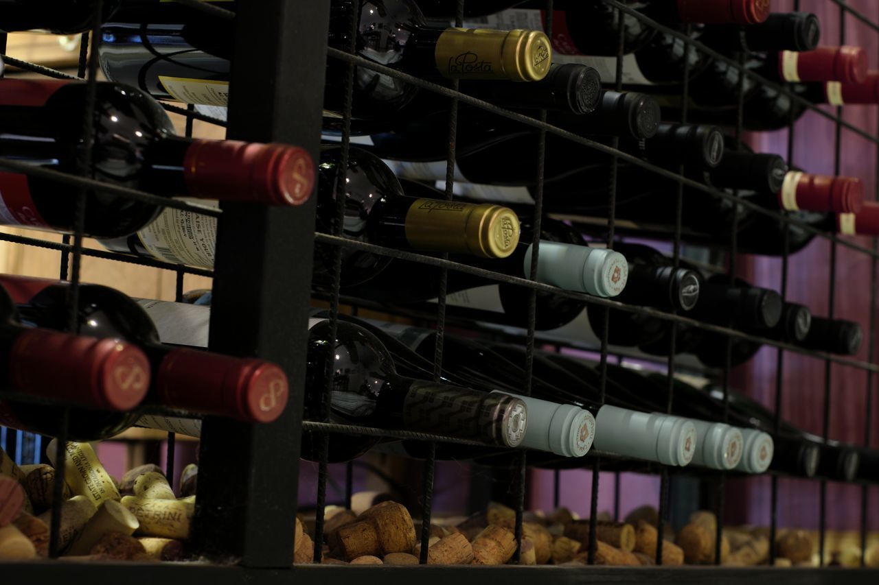 CLOSE-UP OF WINE BOTTLES IN SHELF