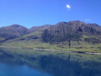 Scenic view of lake and mountains against blue sky