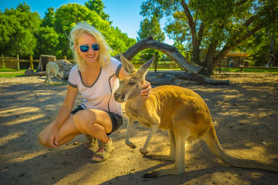 Full length of woman crouching by kangaroo