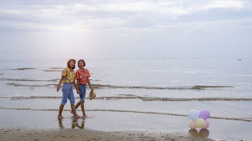 Two young girl walking at the sea at the morning at pranburi.