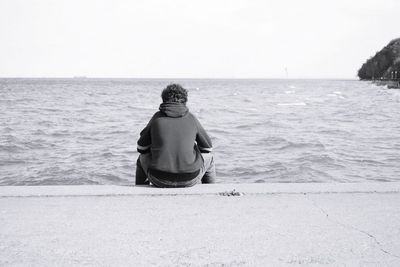 Rear view of man looking at sea against clear sky