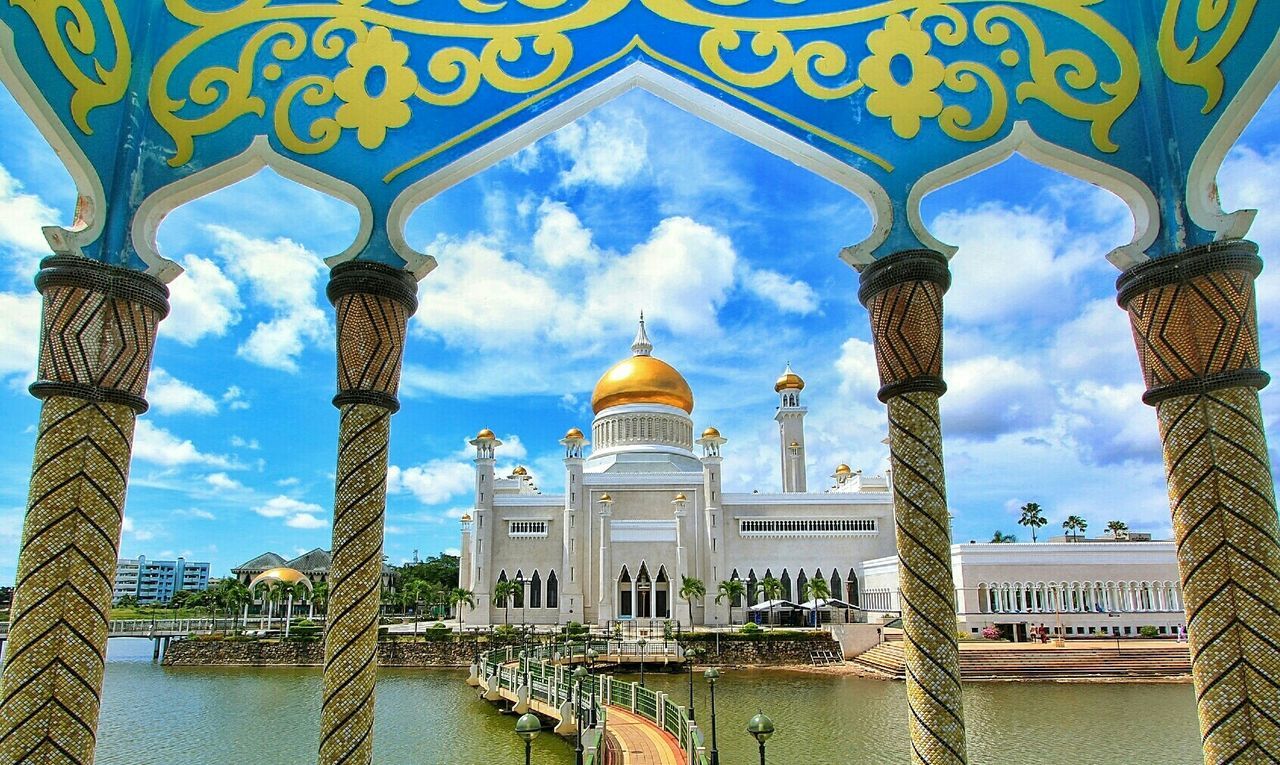 architecture, built structure, sky, building exterior, water, arch, place of worship, cloud - sky, religion, dome, spirituality, waterfront, famous place, architectural column, travel destinations, reflection, mosque, tourism, cloud, history