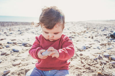 Cute girl sitting on sand at beach