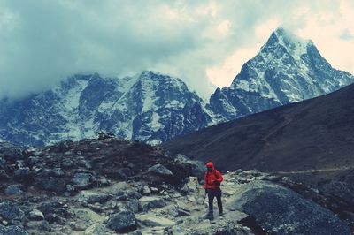 Full length of person trekking on snowcapped mountain against sky