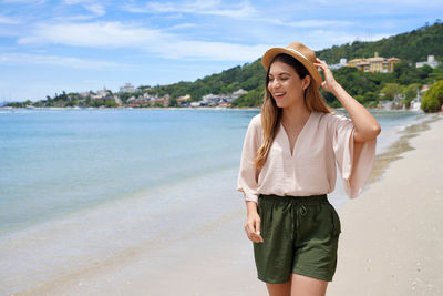 Happy stylish young woman walking on jurere beach, florianopolis, santa catarina island, brazil