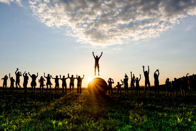 Silhouette people standing on field against sky during sunset