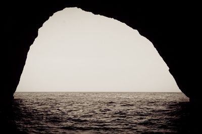 Scenic view of sea against clear sky seen through cave