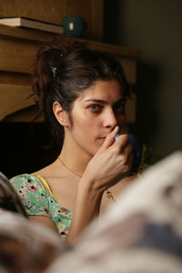 Portrait of young woman looking away while sitting at home