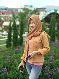 Portrait of smiling young woman standing against plants