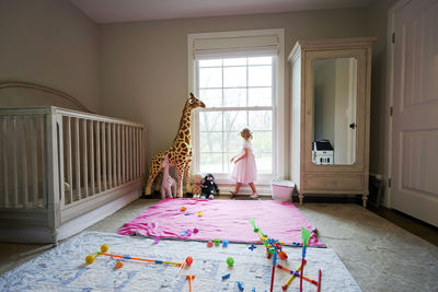 Little toddler girl in a pink dress looking out her bedroom window