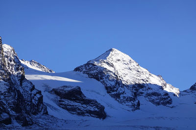 Scenic view of snowcapped mountains against clear blue sky