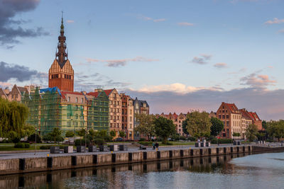 Buildings at waterfront against cloudy sky