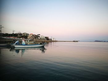 Boats moored at harbor against clear sky