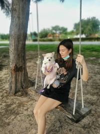 Portrait of young woman sitting on swing