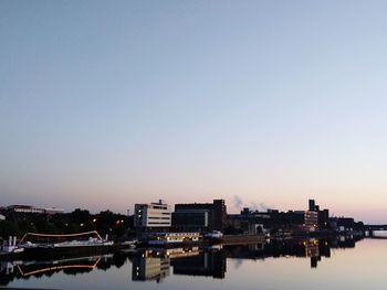 River by city against clear sky during sunset