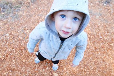 High angle view of cute boy wearing hooded jacket standing at park