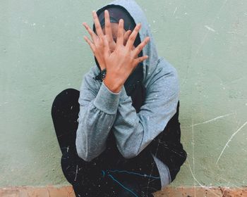 Cropped image of hand holding leaf against wall