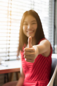 Portrait of smiling young woman gesturing thumbs up
